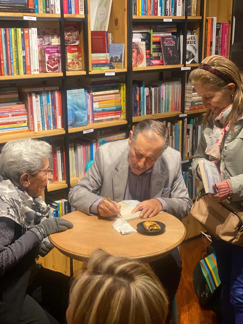 Juan Manuel Ramírez Pérez firmando un libro junto a las lectoras